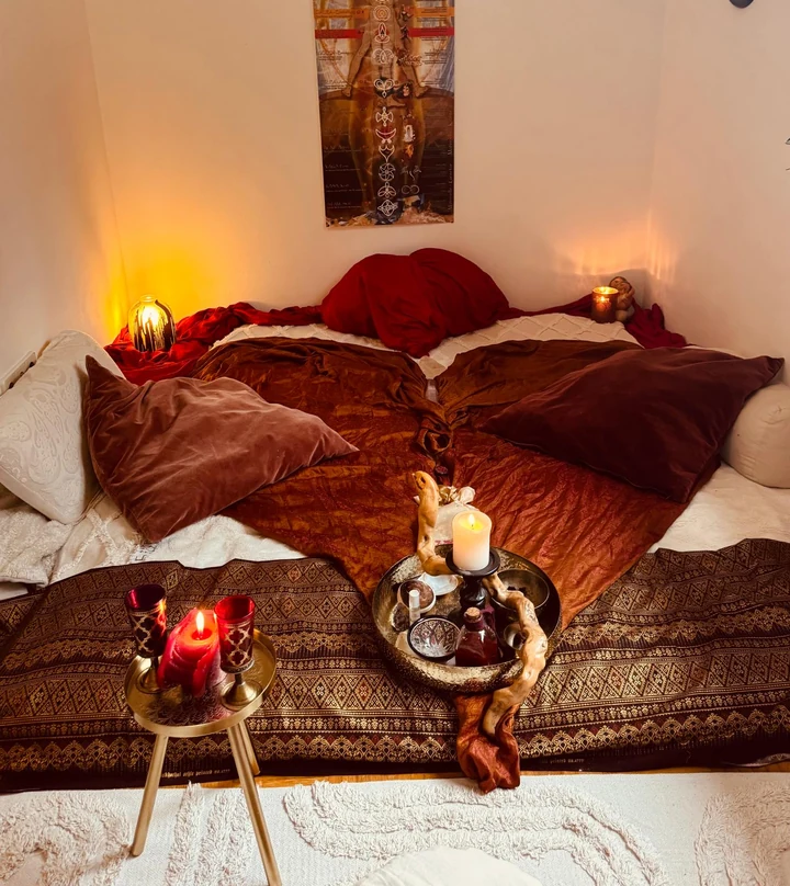 Ein warm beleuchteter Raum mit weichen Decken, Kissen und Kerzen